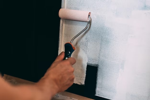 Artisan peintre appliquant une peinture claire au rouleau sur un mur intérieur à Montpellier
